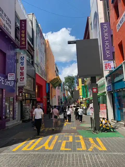 Einkaufsstraße Myeongdong gesäumt von bunten K-Beauty-Läden und Apotheken – Holika Holika rechts sichtbar