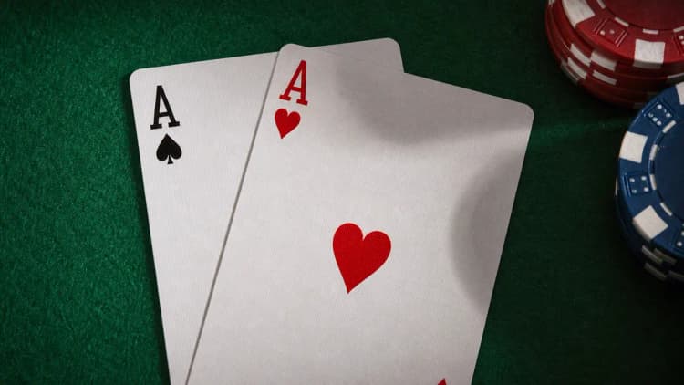 Pocket aces — the ace of spades and ace of hearts freshly dealt on green felt beside poker chips