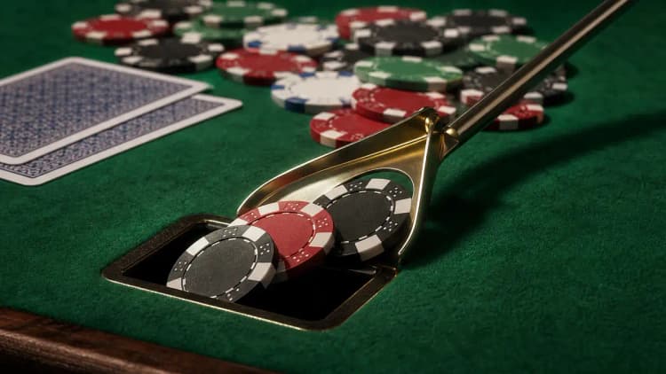 Ein Dealer fegt ein paar Chips aus der Mitte des Pots in den Rake-Schlitz des Tisches, bevor er den Rest zum Gewinner schiebt